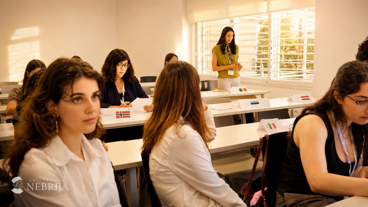 Un grupo de estudiantes en una sala de clase, con una persona de pie frente a ellos presentando.