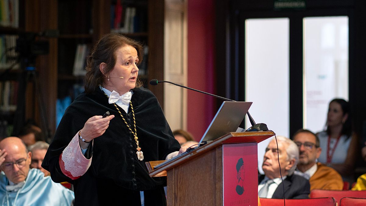 Una mujer habla frente a un público en un acto académico.