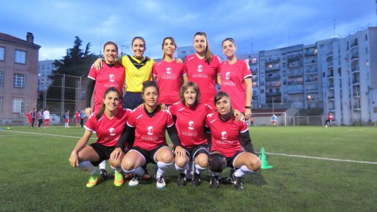 Un grupo de jugadoras de fútbol posando en un campo durante el atardecer.