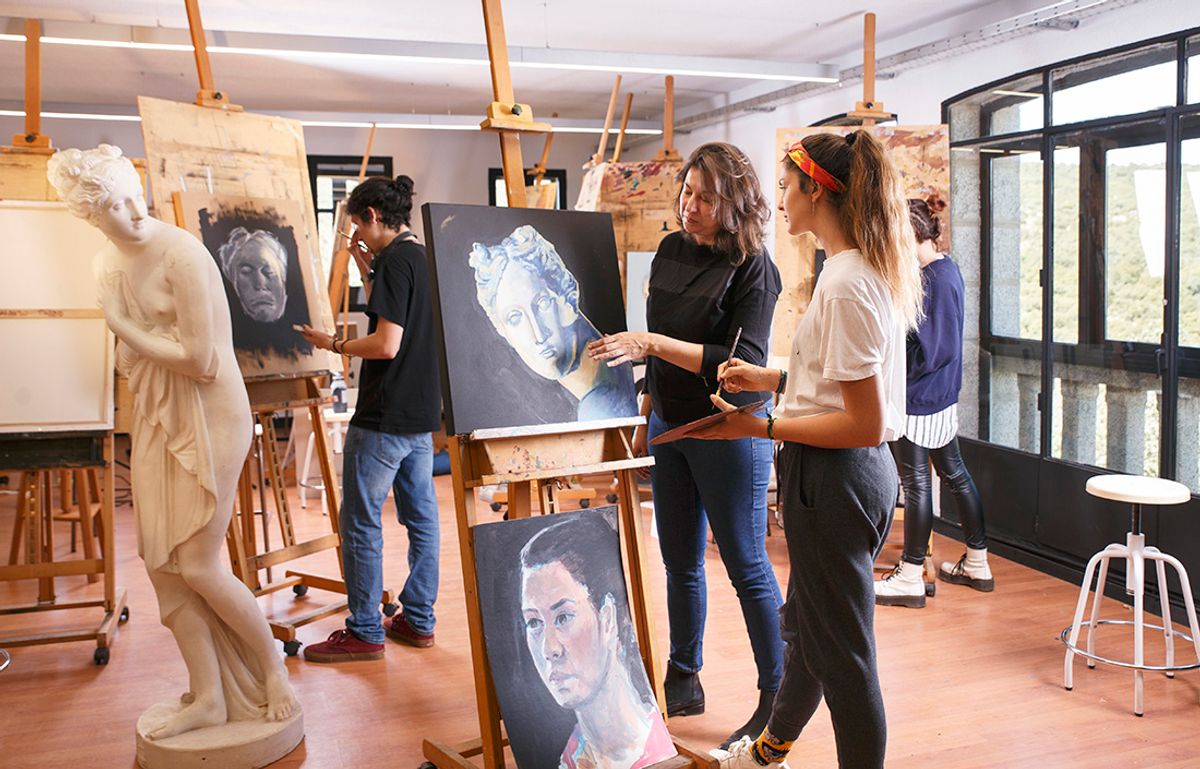 Una clase de arte en la que estudiantes están trabajando en sus retratos mientras observan una escultura.