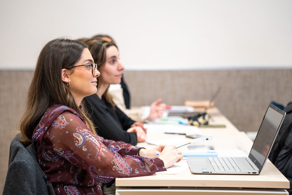 Dos mujeres sentadas en un aula prestando atención durante una clase.