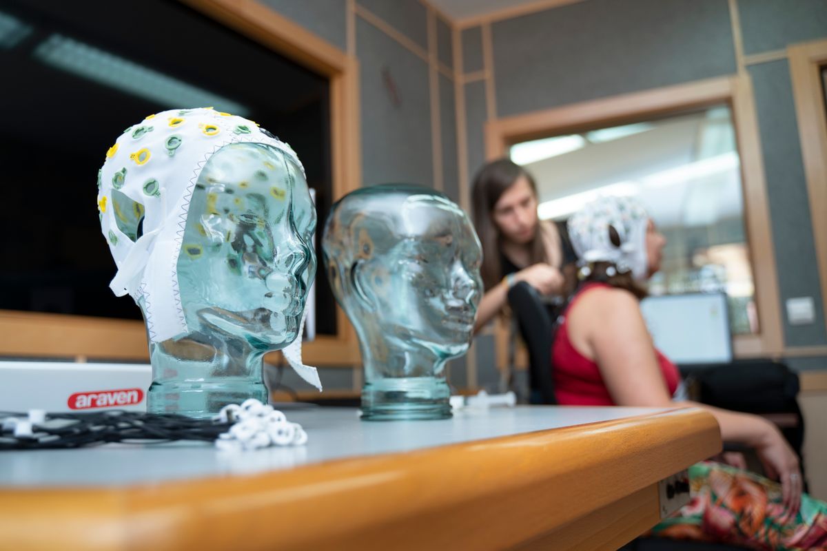 La imagen muestra cabezas de cristal con dispositivos de monitoreo y una persona preparándose para una prueba neurológica.