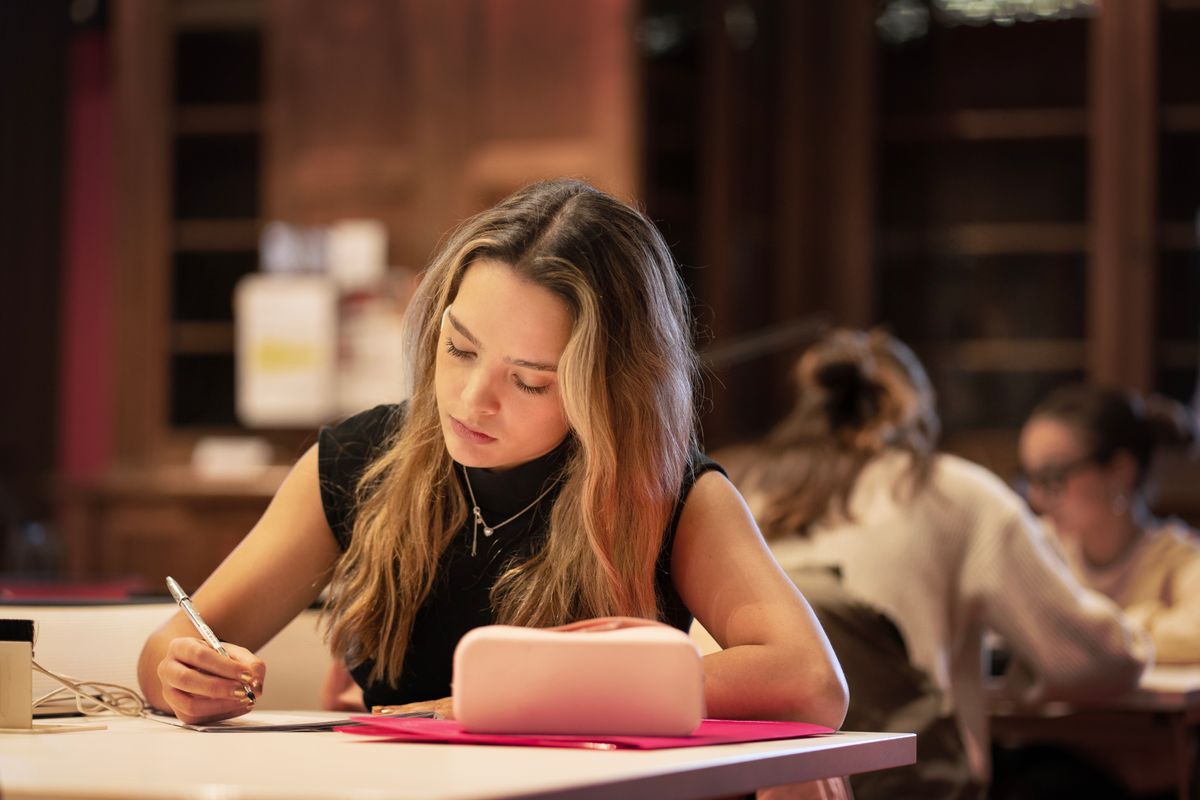 Una joven estudia concentrada en una mesa con útiles escolares.