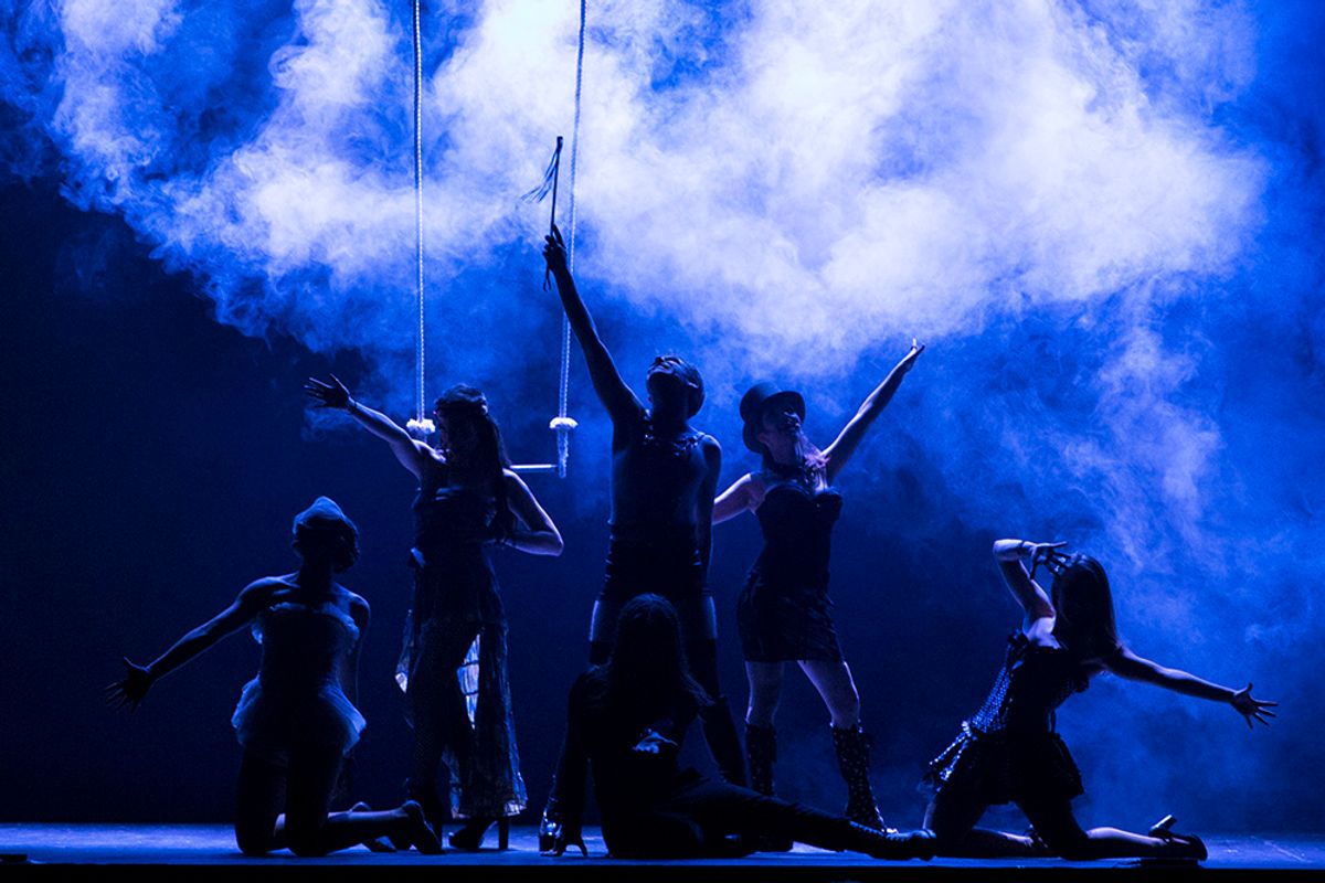 Un grupo de personas se presenta en una actuación teatral con humo y luces de fondo.