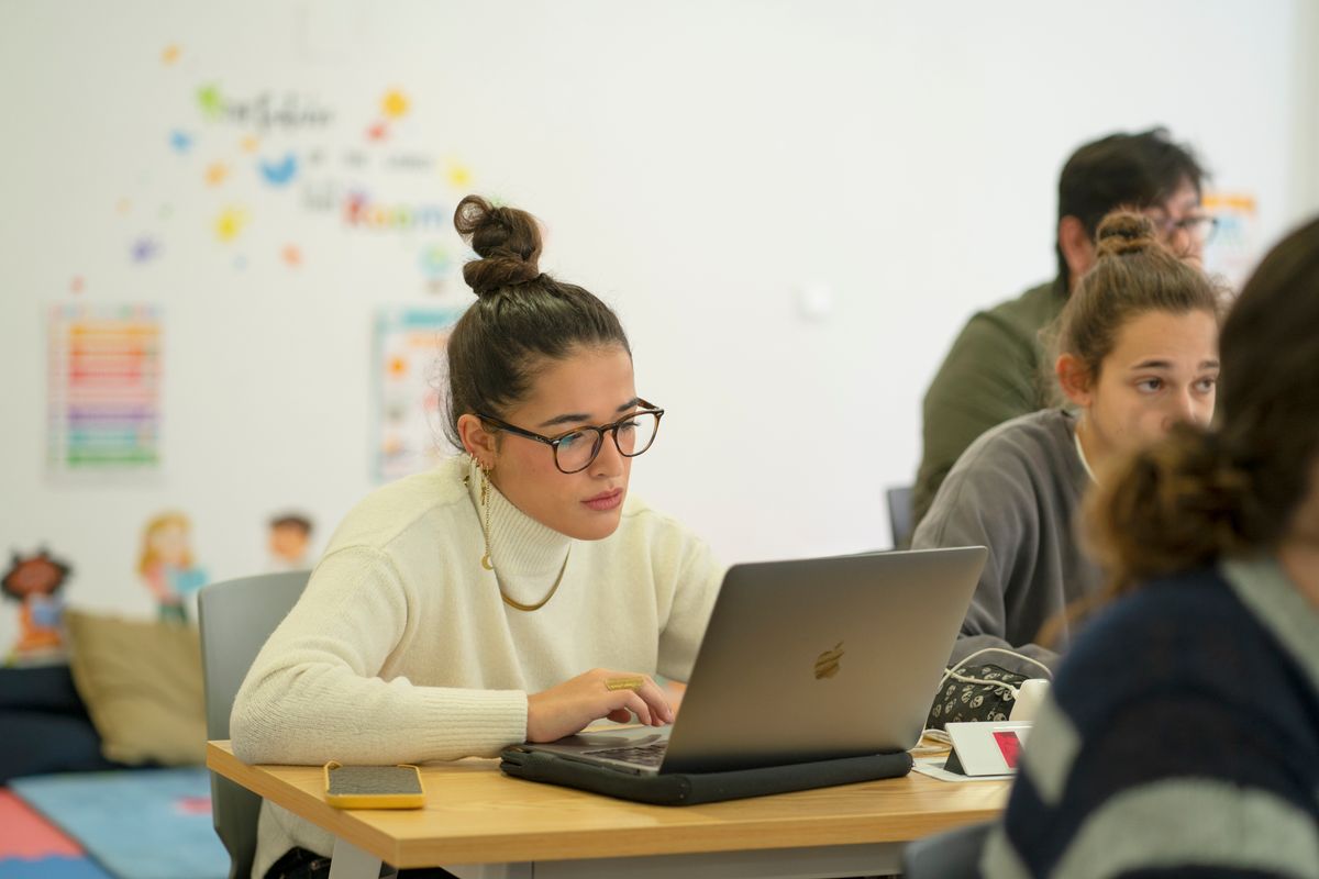 Una estudiante trabaja en su computadora portátil en un aula moderna.