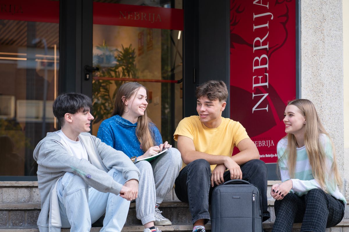 Un grupo de cuatro estudiantes conversando en la entrada de una universidad.