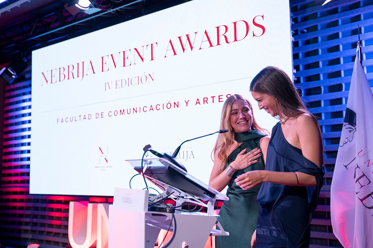 Dos mujeres presentan un evento relacionado con los Premios Nebrija en un ambiente festivo.