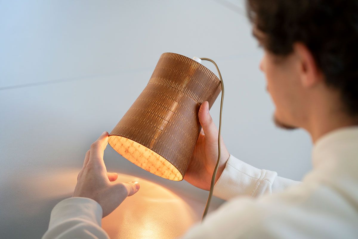 Una persona sostiene una lámpara de diseño moderno con luz encendida.