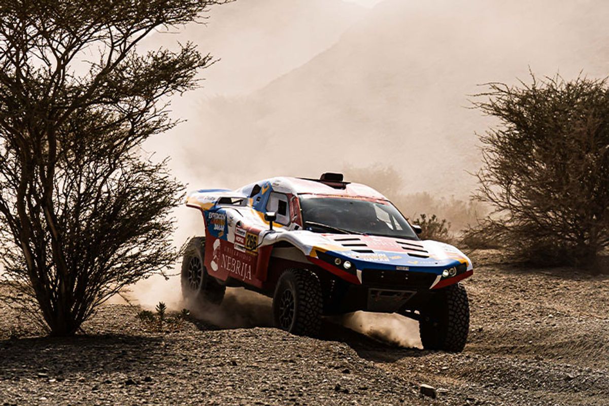 Un vehículo todoterreno compitiendo en un paisaje árido y polvoriento.