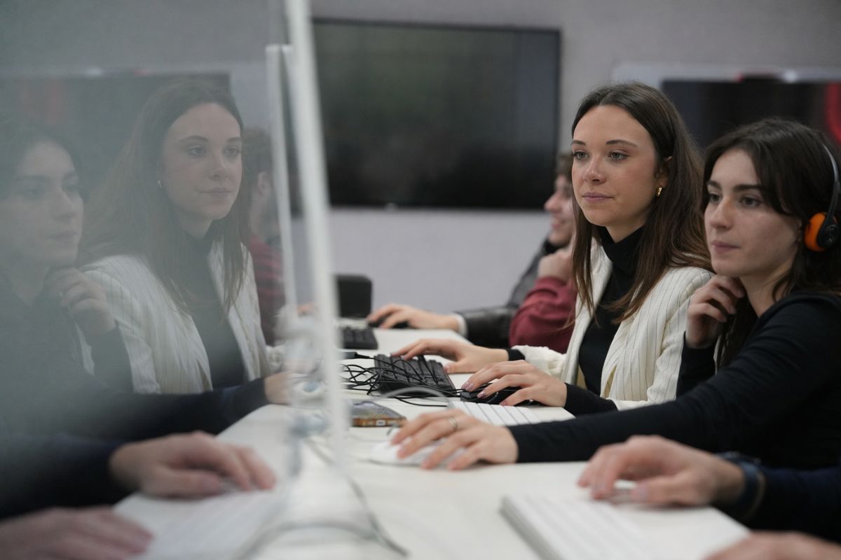 Dos mujeres se encuentran trabajando en un ordenador en un entorno colaborativo.