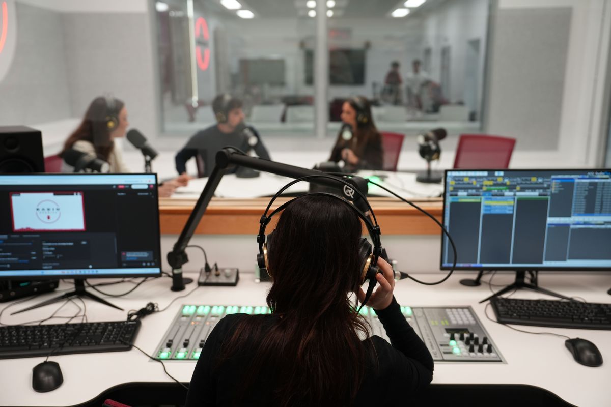 Un grupo de personas interactúa en un estudio de grabación de radio.