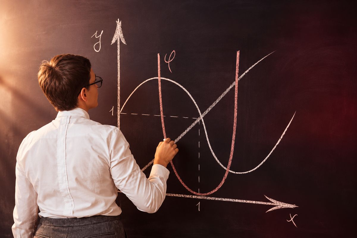 Una persona está dibujando gráficos matemáticos en una pizarra.