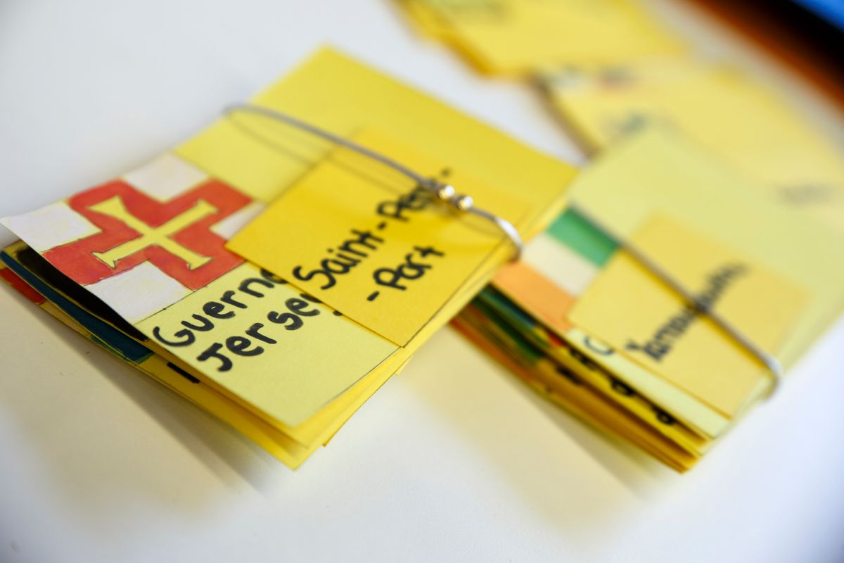 Una colección de tarjetas amarillas que incluyen nombres y banderas de diferentes lugares.