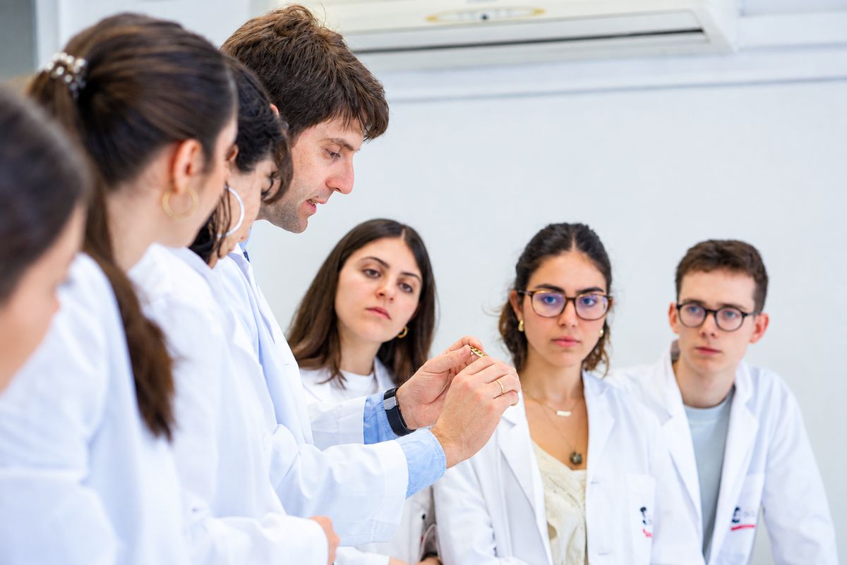 Un grupo de estudiantes de ciencias observa atentamente a un profesor durante una clase práctica.