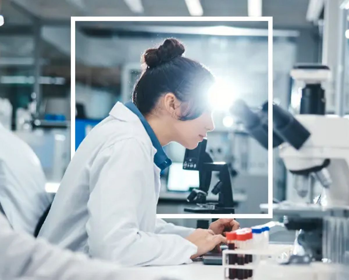 Una científica observa a través de un microscopio en un laboratorio.