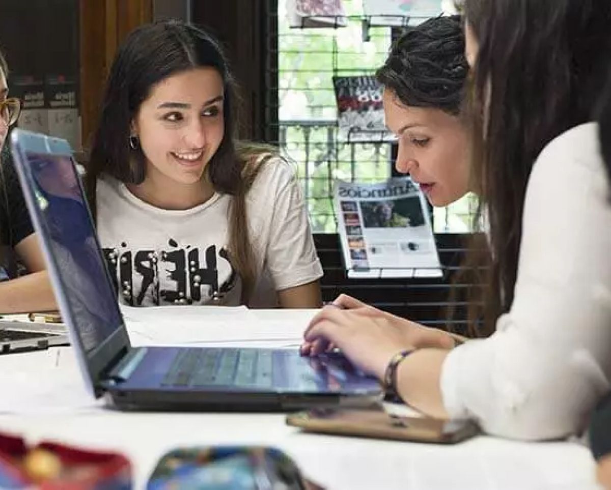 Un grupo de jóvenes están estudiando y colaborando en una tarea frente a una computadora portátil.