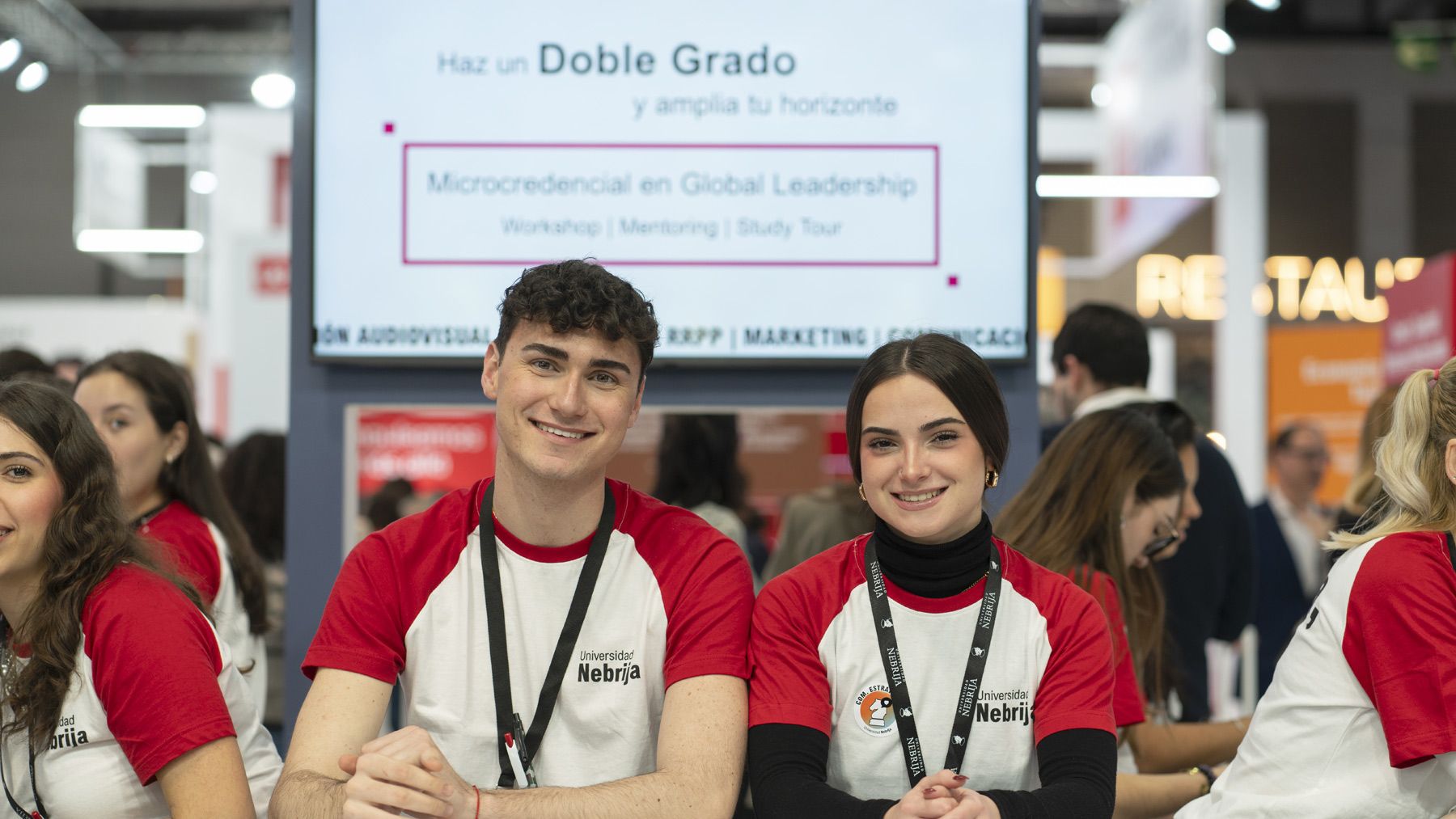 Dos jóvenes sonrientes en la semana de la educación promocionando un programa educativo.