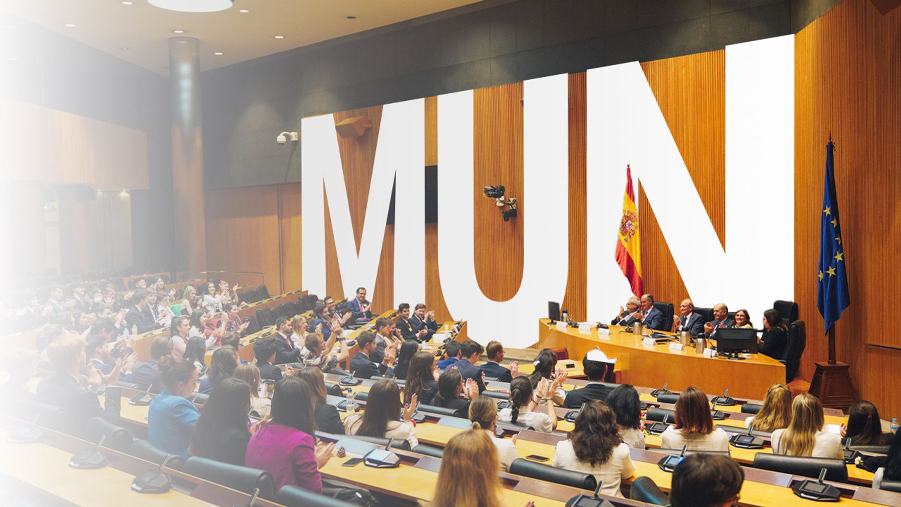 La imagen muestra un evento en un auditorio con el título MUN proyectado en gran tamaño en la pared detrás de los ponentes.
