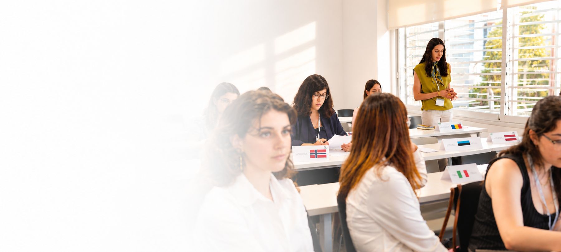 Un grupo de mujeres en un aula, algunas sentadas y una de pie, participando en una actividad de aprendizaje.