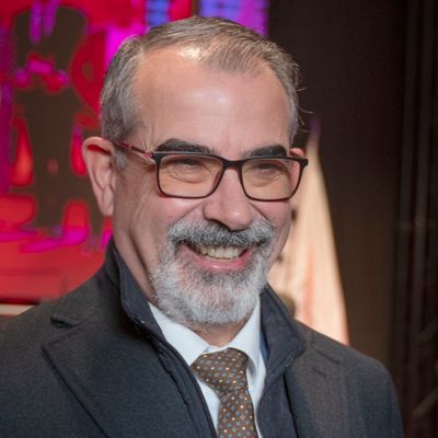 Hombre con gafas y barba sonriente en un evento formal.