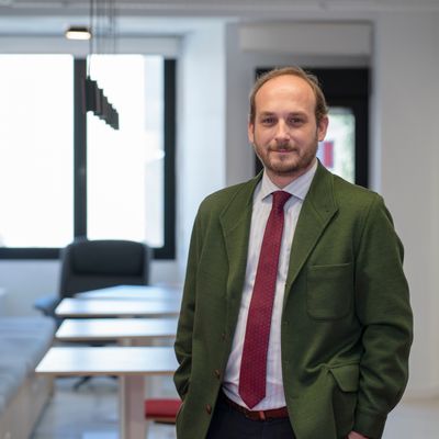 Un hombre de pie en un espacio moderno de oficina con ventanas grandes.