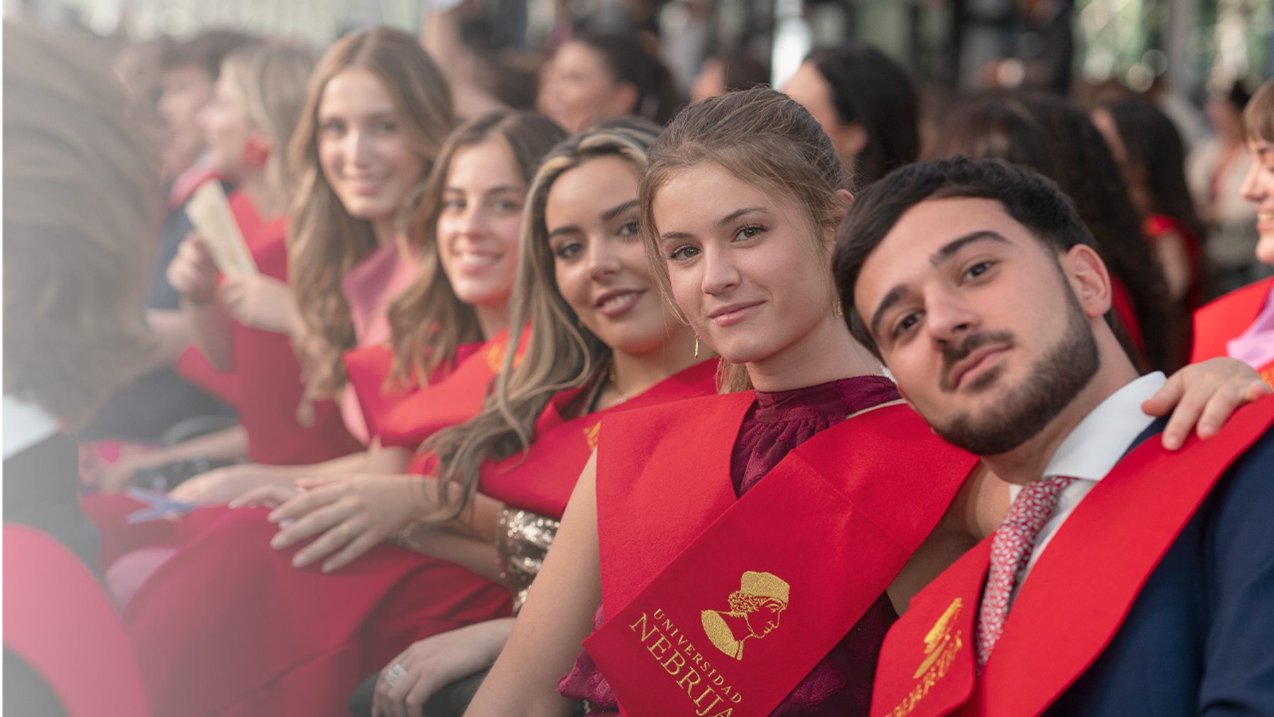 Un grupo de graduados sonríe mientras posan con sus togas y fajas de graduación.