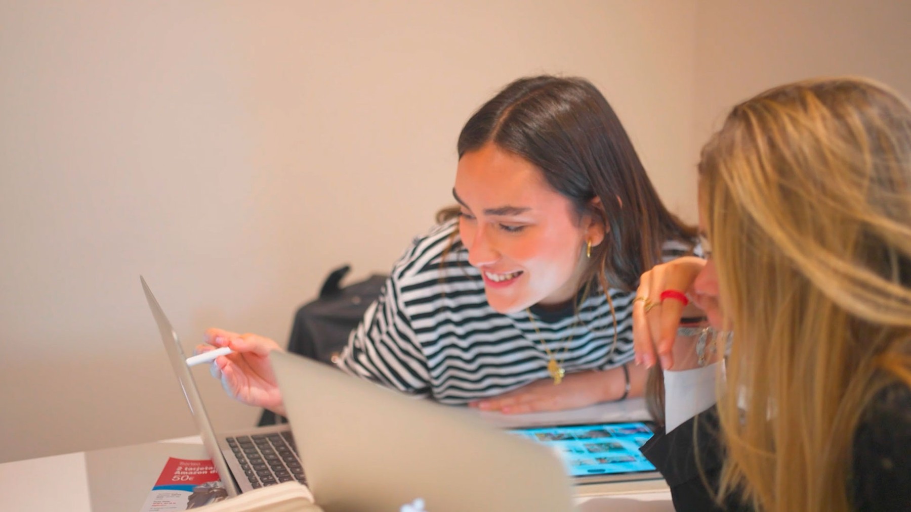 Dos jóvenes se ríen mientras trabajan en una computadora portátil en un ambiente acogedor.