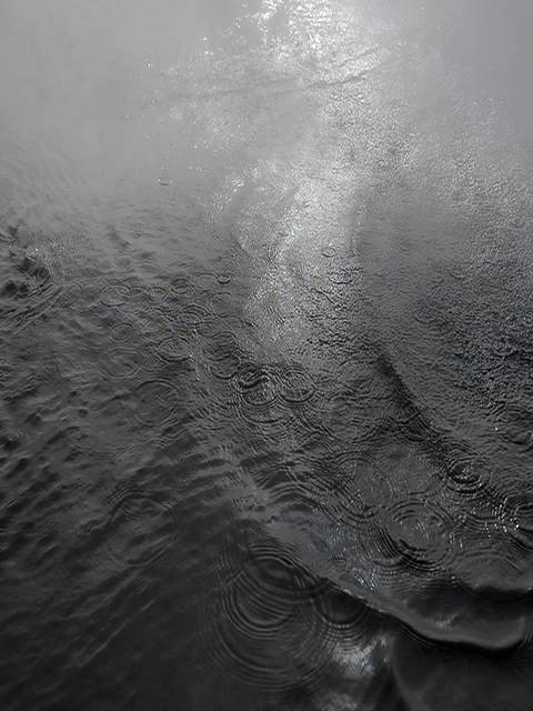 Superficie del agua con reflejos y ondas en un ambiente de niebla.