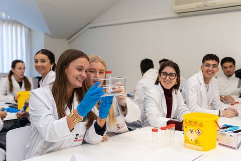 Un grupo de estudiantes en laboratorio se divierten mientras realizan un experimento con tubos de ensayo.