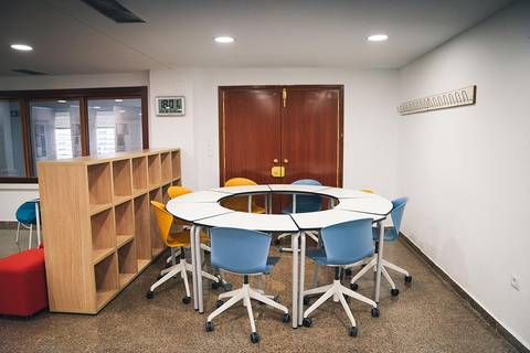 Una sala de reuniones moderna con una mesa circular y sillas de colores.