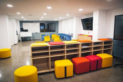 Una sala moderna con muebles coloridos y un ambiente acogedor para trabajar o estudiar.