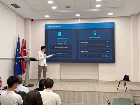 Una persona presenta un modelo de negocio en una pantalla grande durante un evento o conferencia.