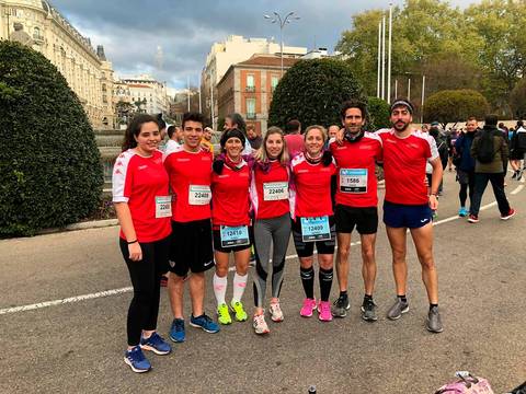 Un grupo de deportistas sonrientes posan juntos antes de una carrera, todos vestidos con camisetas rojas.
