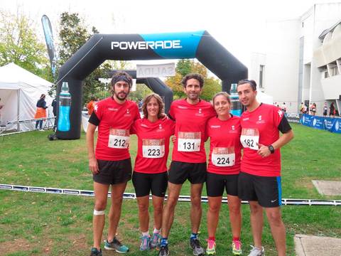 Un grupo de cinco corredores posan en un evento deportivo bajo un arco de llegada.