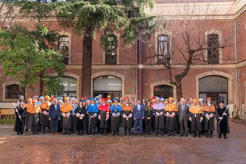 Un grupo de personas vestidas con trajes formales y coloridos posa en un patio de edificio antiguo.