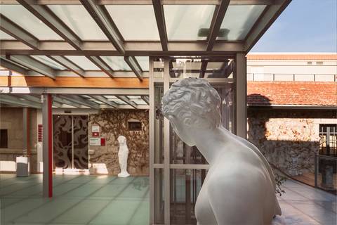 La imagen muestra una escultura blanca en un entorno arquitectónico moderno y luminoso.