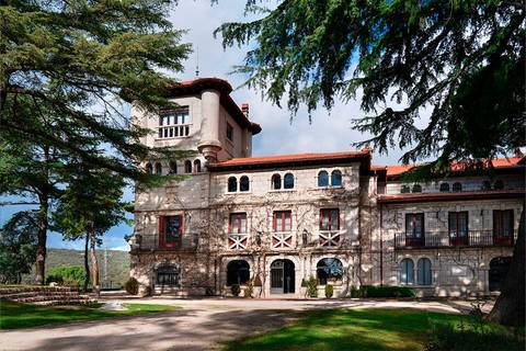 Una majestuosa mansión de estilo arquitectónico clásico rodeada de árboles y un paisaje verde.