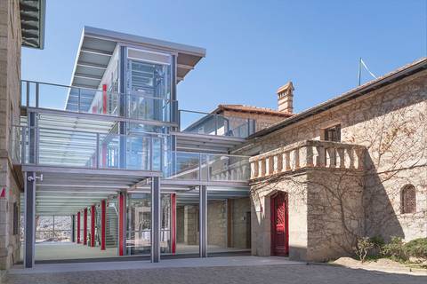 Un edificio moderno de vidrio y acero se integra con una construcción histórica de piedra.
