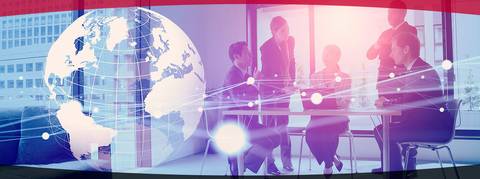 Imagen que muestra un grupo de personas en una reunión con un mapa mundial en el fondo, sugiriendo un contexto de negocios y globalización.