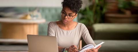 Una mujer joven estudia frente a un ordenador portátil en un ambiente acogedor.