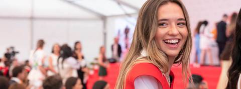 Una joven sonriente asiste a un evento social entre una multitud.