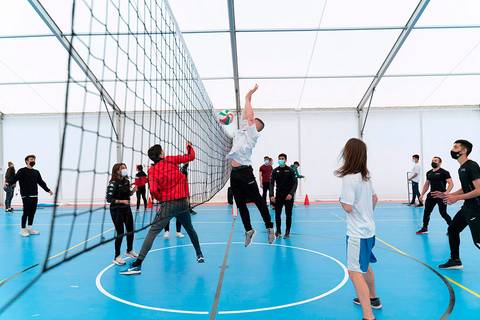 Un grupo de personas juega al voleibol en un gimnasio cubierto.