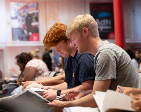 Dos jóvenes estudiando y leyendo en un ambiente académico.