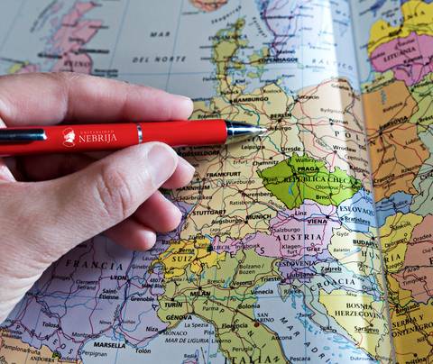 Una mano sostiene un bolígrafo rojo sobre un mapa de Europa.