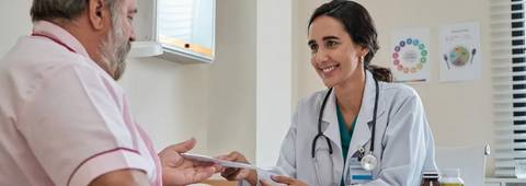 Una doctora conversa amablemente con un paciente en un consultorio médico.