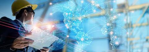 Un profesional con casco de seguridad observa un mapa digital interconectado mientras sostiene una tableta.