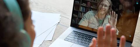 Una persona saluda a través de una videollamada en un ordenador portátil.