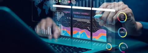 Una persona está analizando datos en una laptop mientras observa gráficos en pantallas digitales.