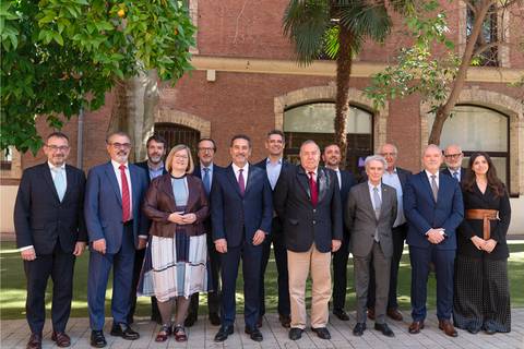 Grupo de personas posando en un entorno al aire libre, con árboles y un edificio de fondo.