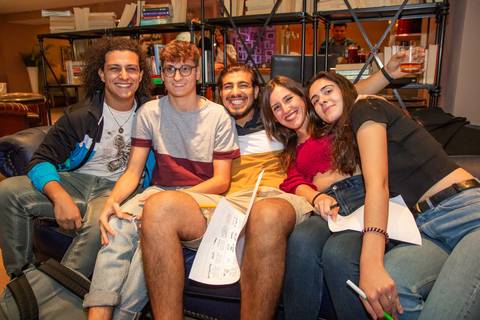 Un grupo de cinco jóvenes posando juntos en un sofá, sonriendo y disfrutando del momento.